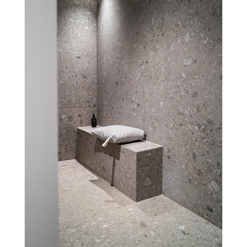 Hellgraues Badesofa Sitzkissen auf moderner Duschbank in grauer Natursteinumgebung